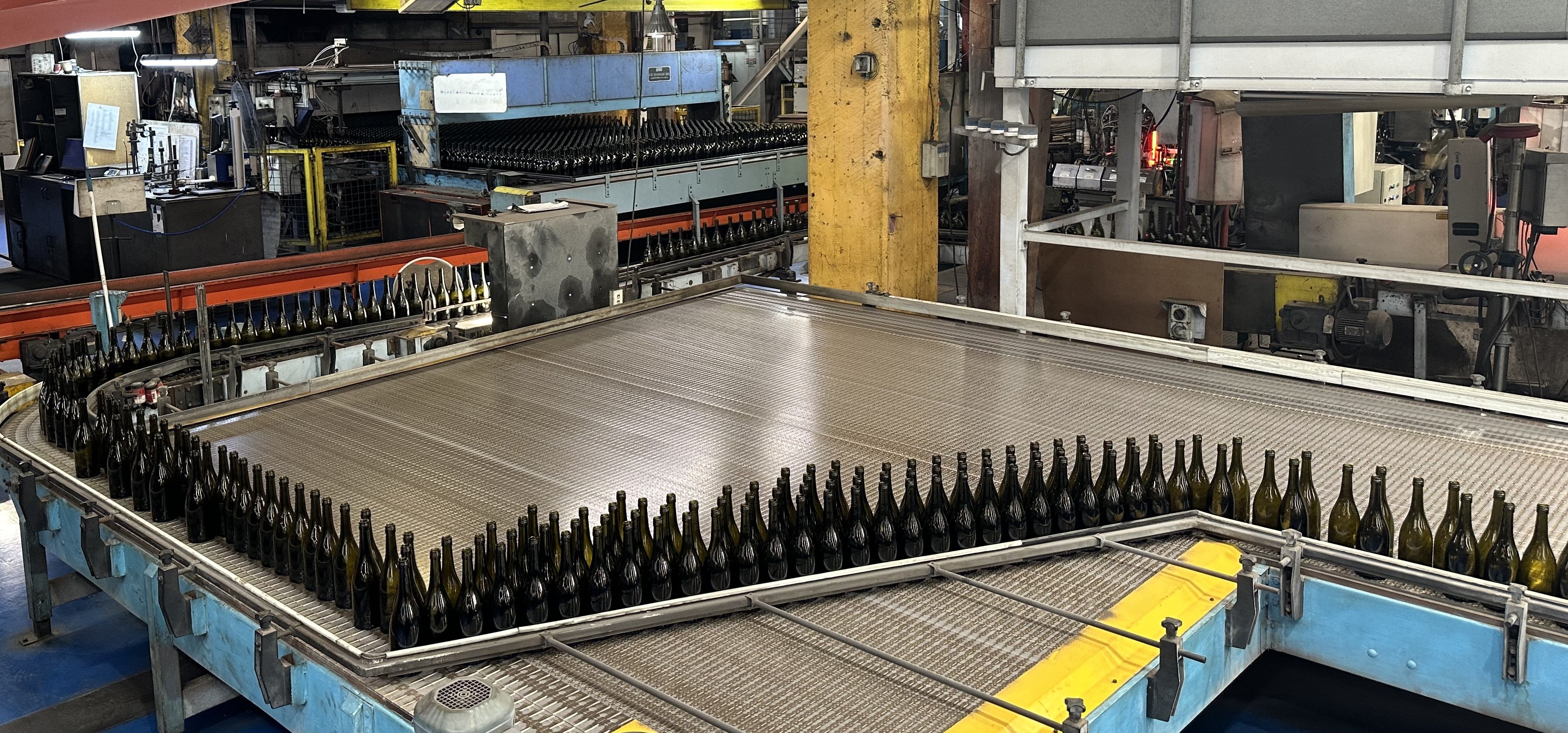 Brown glass bottles on a conveyor belt in a glass manufacturing facility