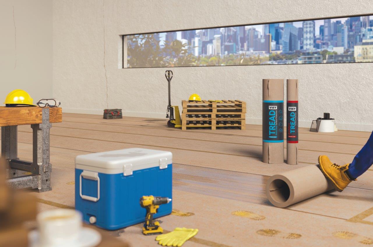 A room being renovated with a large window showing a city skyline through it. There are various builders tools, including rolled up brown paper for surface protection