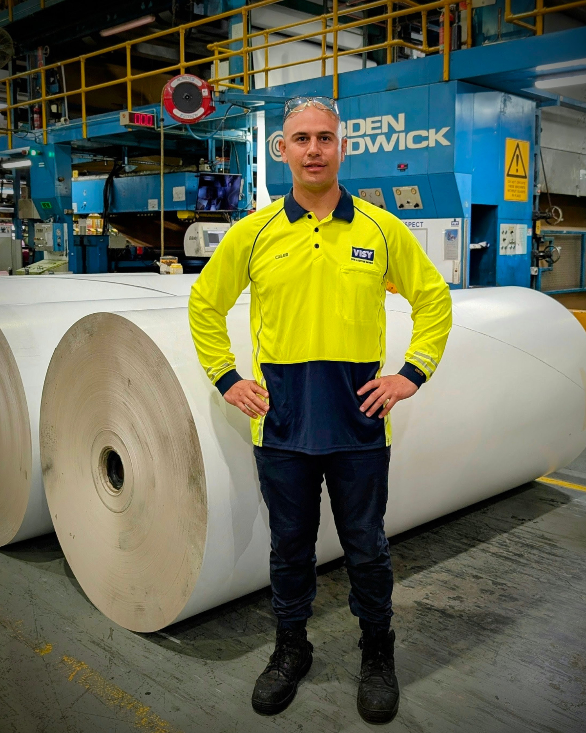 Man in high-vis top and safety goggles stands in front of Visy site