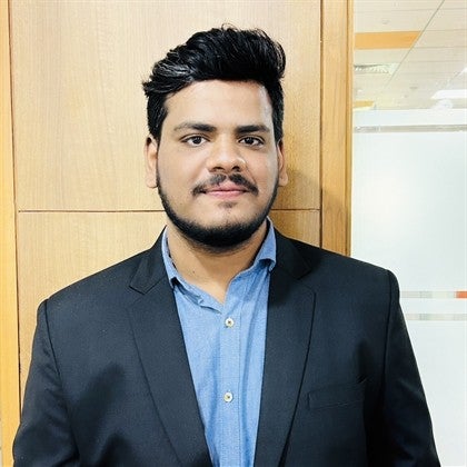 Team member Dheeraj, wearing a dark jacket, smiles at the camera