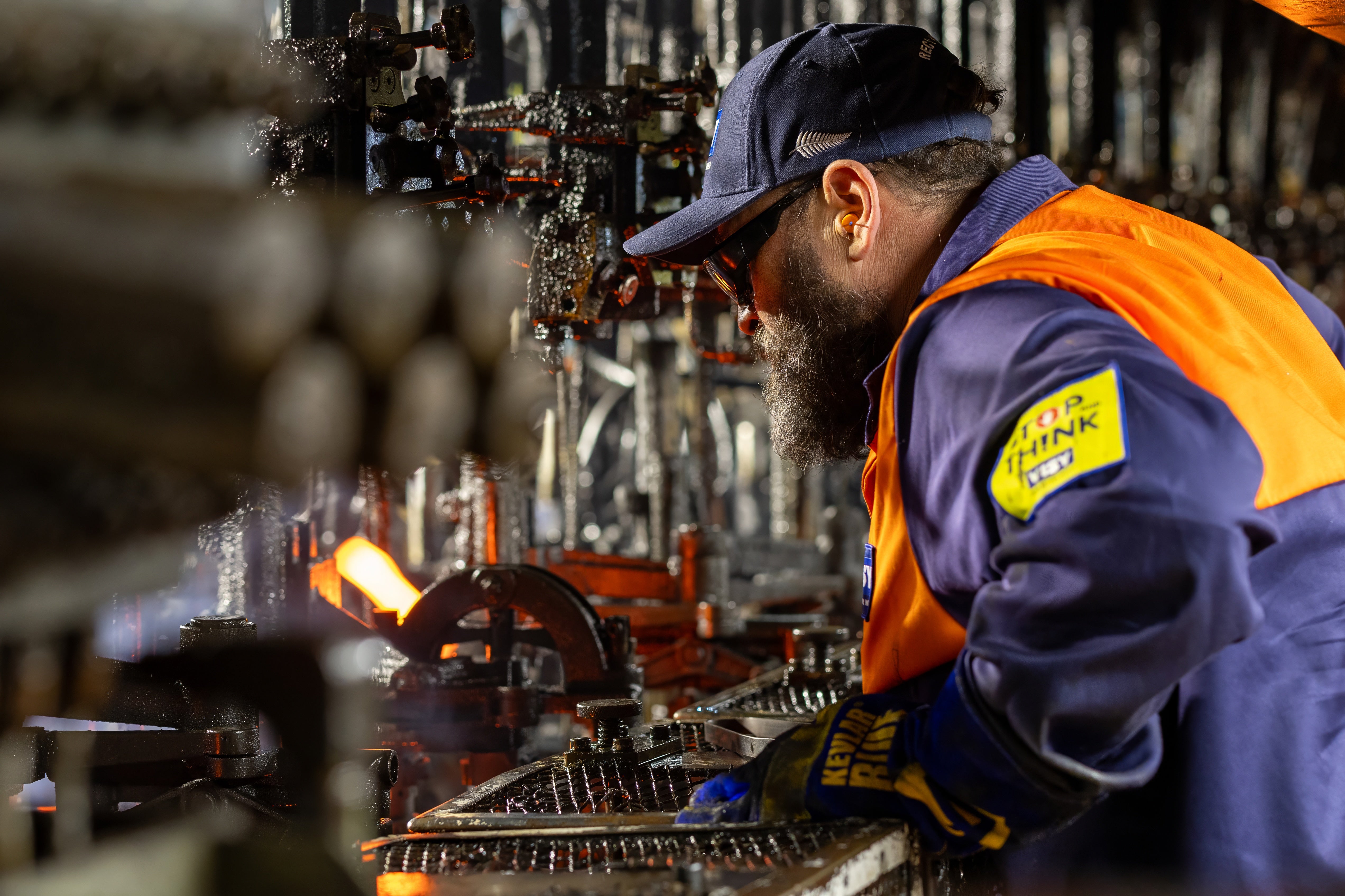 Man in high visibility safety gear working at the hot end of glass manufacturing