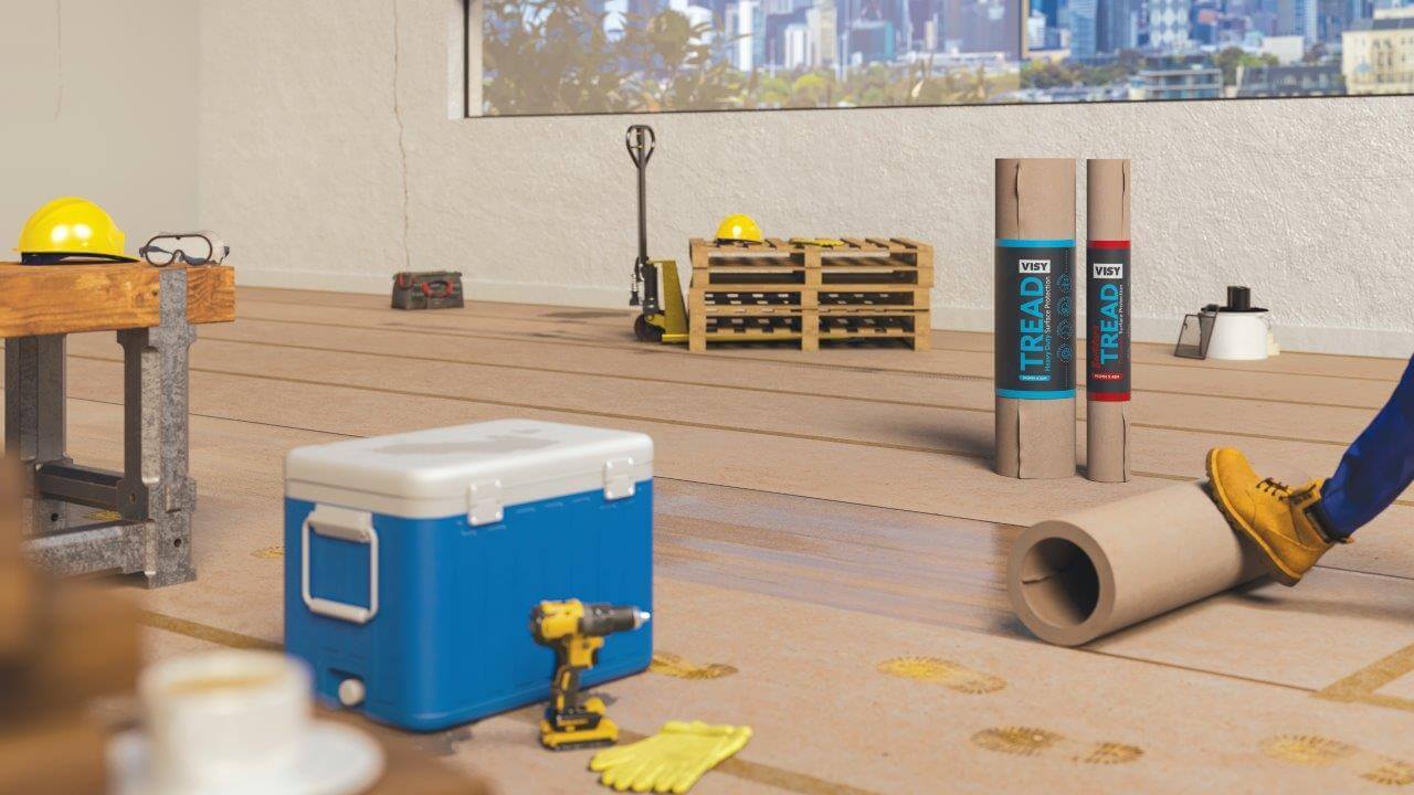 A room being renovated with a large window showing a city skyline through it. There are various builders tools, including rolled up brown paper for surface protection