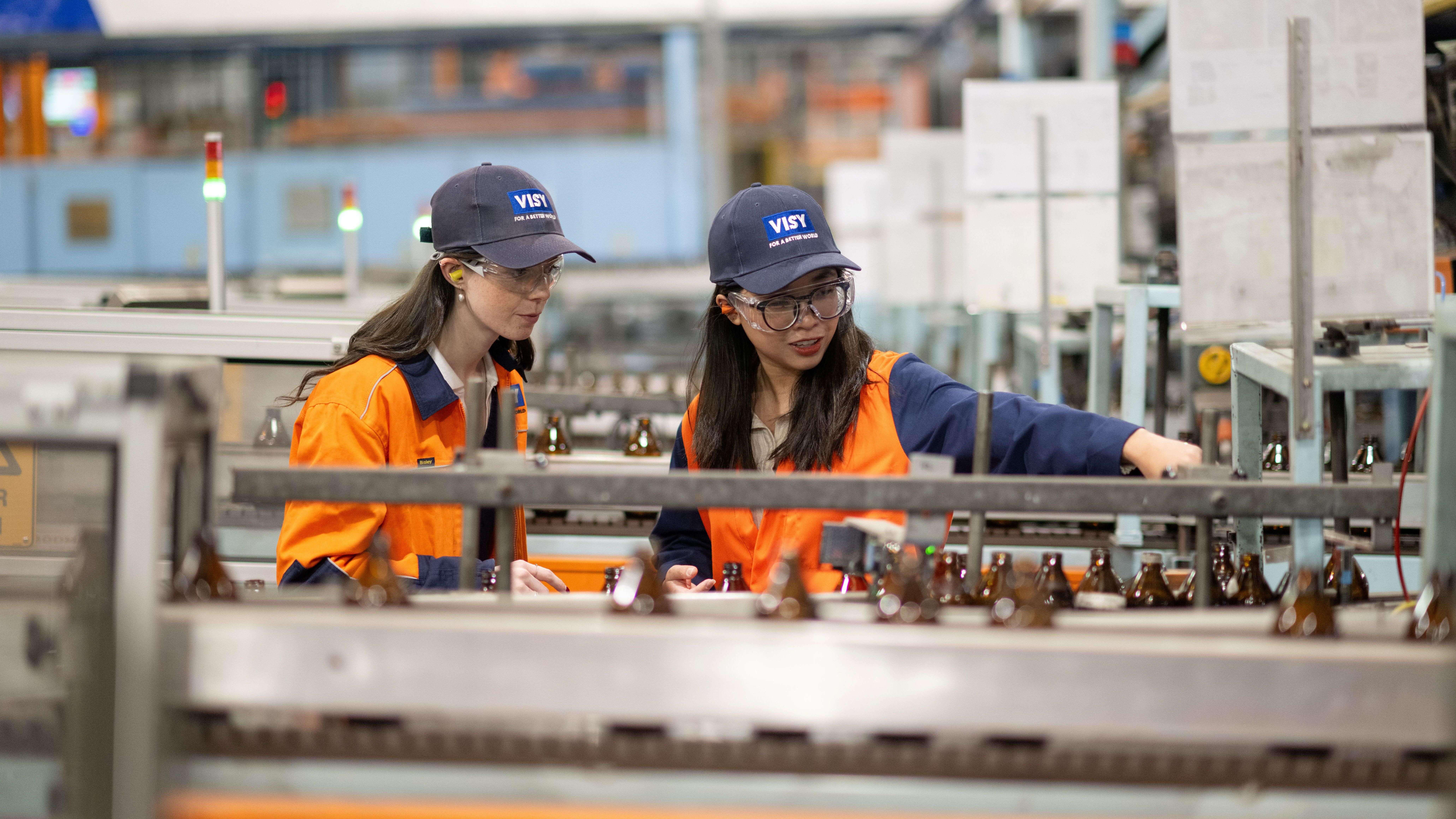 Two girls pointing and inspecting glass bottles