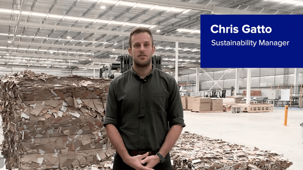 A man wearing a dark green shirt standing in front of bales of shredded cardboard