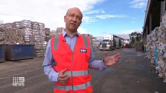 Man in high-vis standing in front of plastics haybales