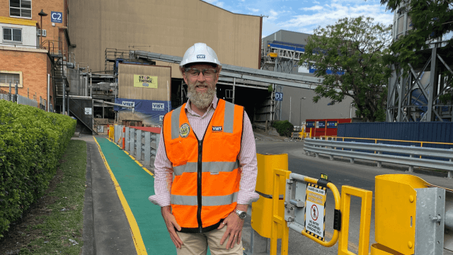 A man standing on a work site in a hi-vis vest