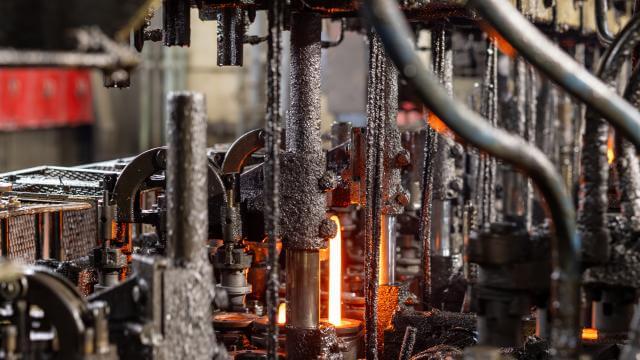 Close-up view of glass production machinery, with a molten gob of glass.