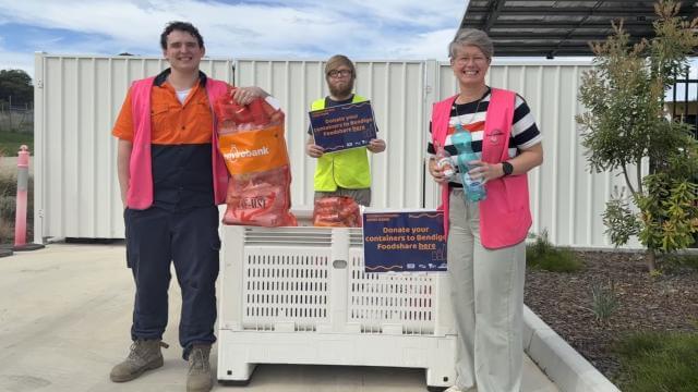 Three people in hi-vis vests stood in front of a Nally bin