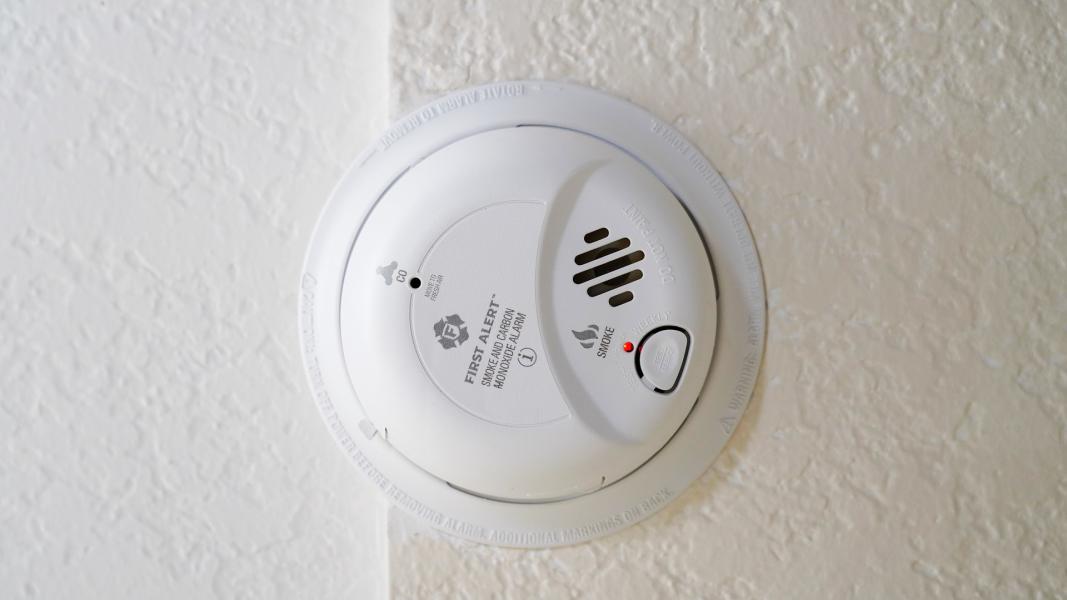 A smoke alarm attached to a white ceiling