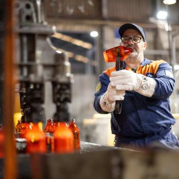 Man at a machine inspecting glass bottle