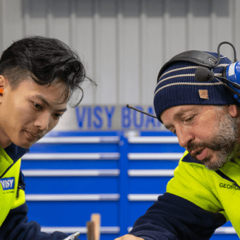 Two team members in high-vis tops examine a printing tool at a Visy Board site.