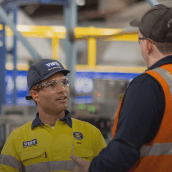 Team wearing PPE talks and smiles together