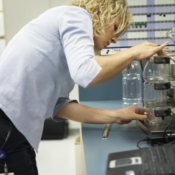 A woman uses high tech machinery to test a plastic bottle