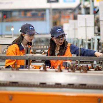 Two girls pointing and inspecting glass bottles