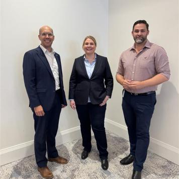 Three people stood together smiling at the camera 