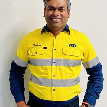 Man wearing yellow high-vis top smiles at the camera.