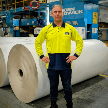 Man in high-vis top and safety goggles stands in front of Visy site