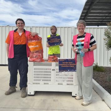 Three people in hi-vis vests stood in front of a Nally bin
