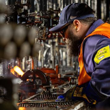 Man in high visibility safety gear working at the hot end of glass manufacturing