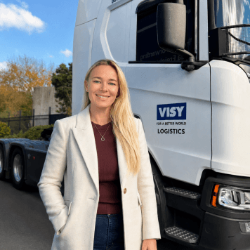 Suzette smiles at the camera, standing in front of a Visy Logistics truck.