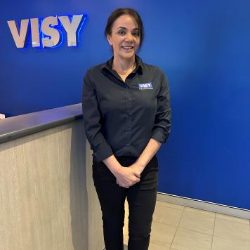 Rose wears a navy blue Visy shirt and smiles at the camera.